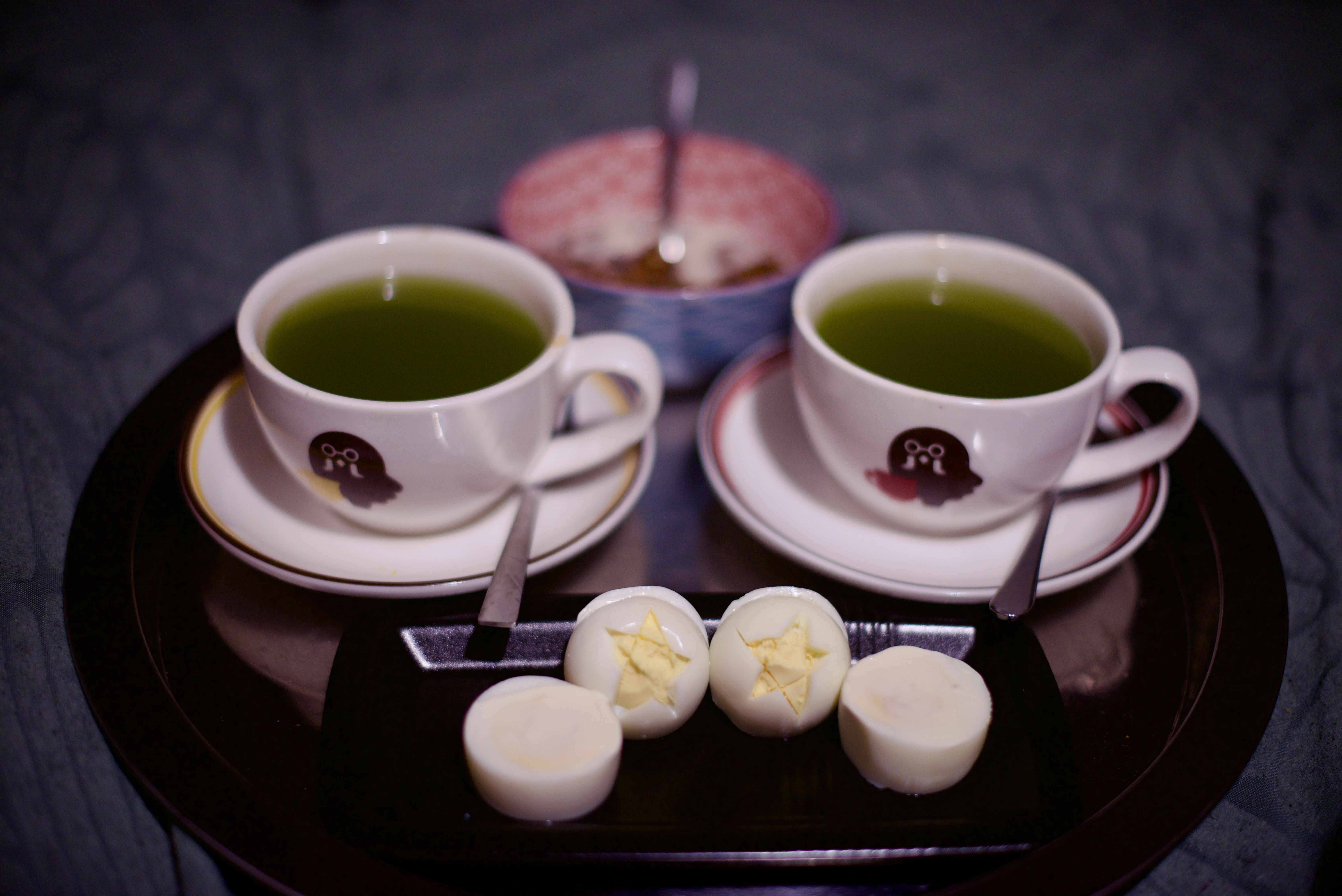 Photo du plateau de petit déjeuner : deux tasses Animal Crossing pleines de thé vert, un bol de céréales, deux œufs durs dans lesquels j'ai sculpté des pentacles dans le gros bout des blancs pour laisser apparaître le jaune.