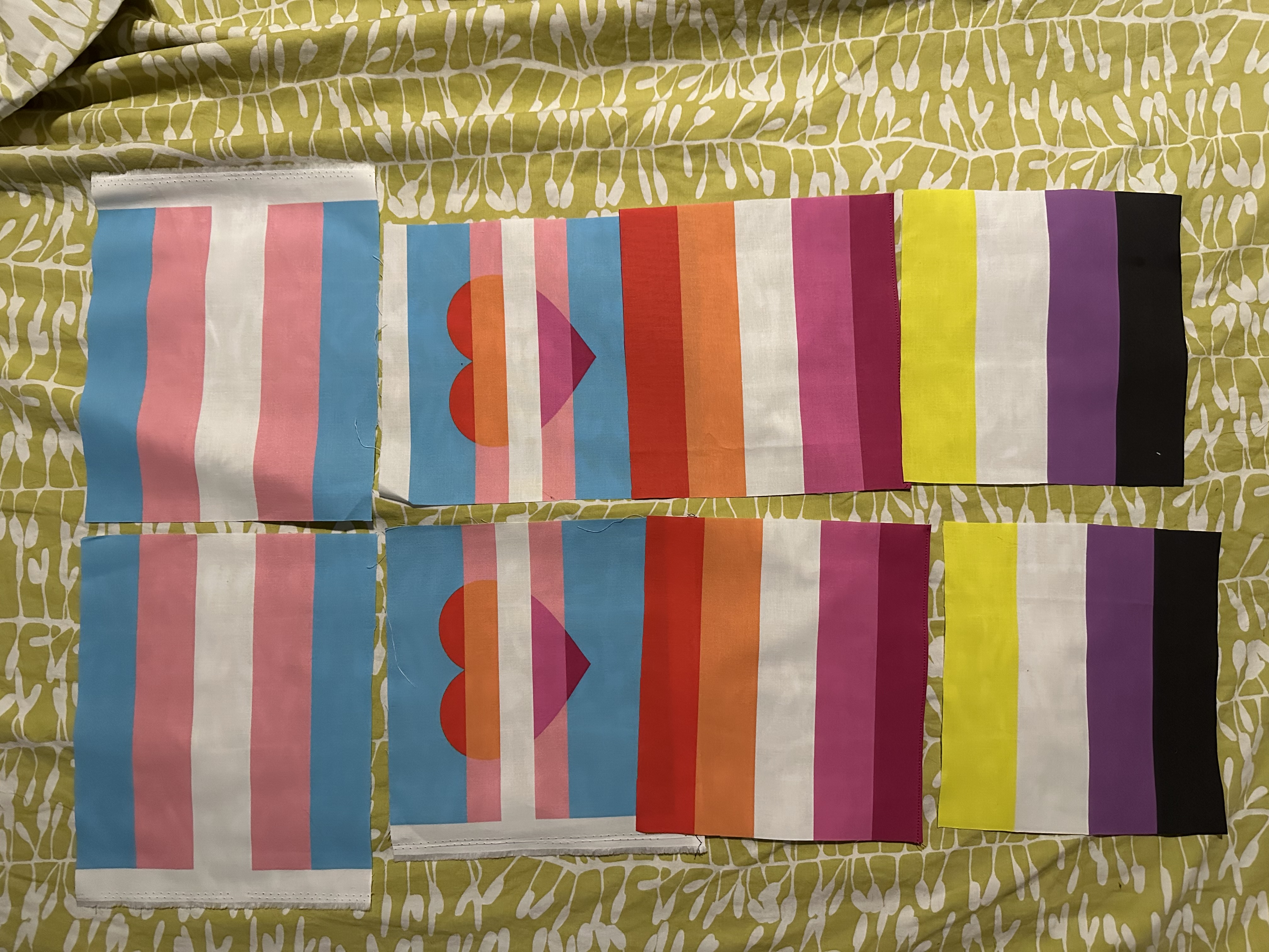 huit drapeaux de fiertés à plat sur un drap, comme décris dans le texte