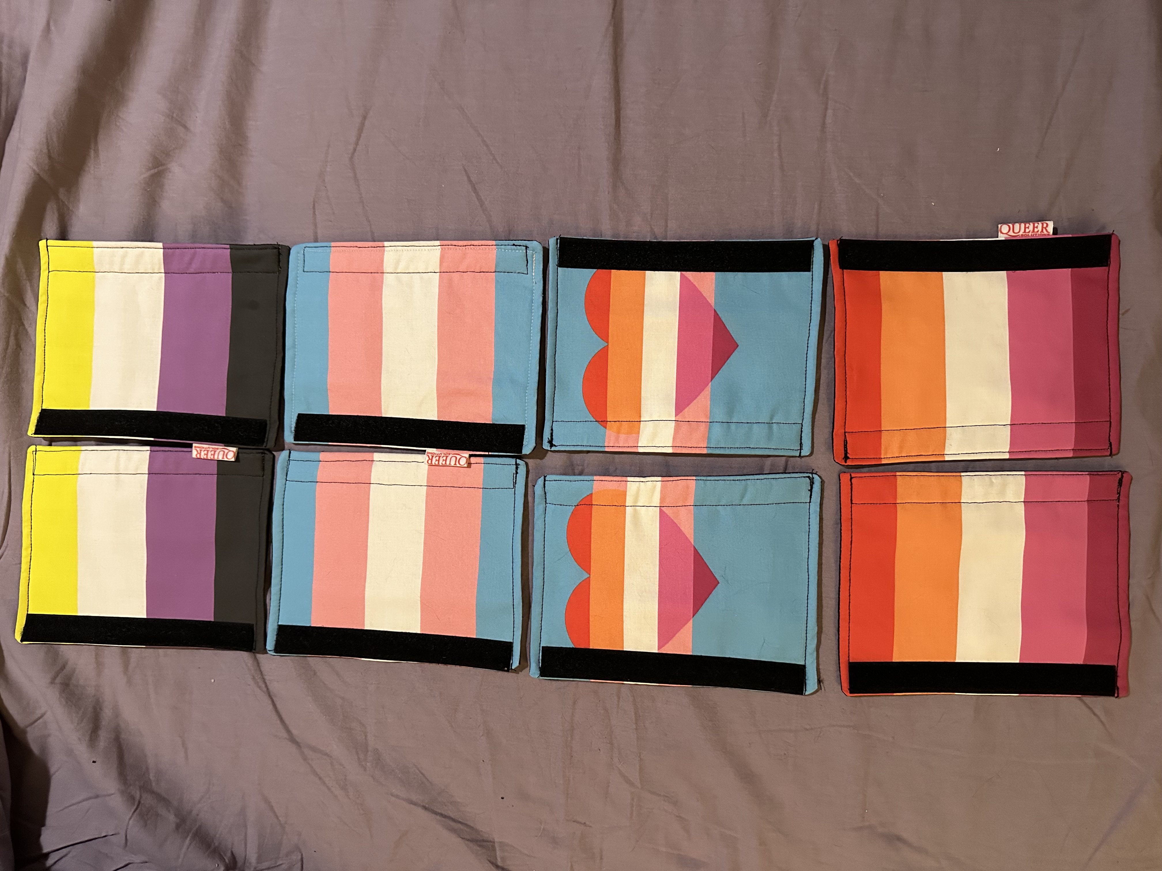 huit protections de ceinture de sécurité terminées, cousues dans les drapeaux de fierté