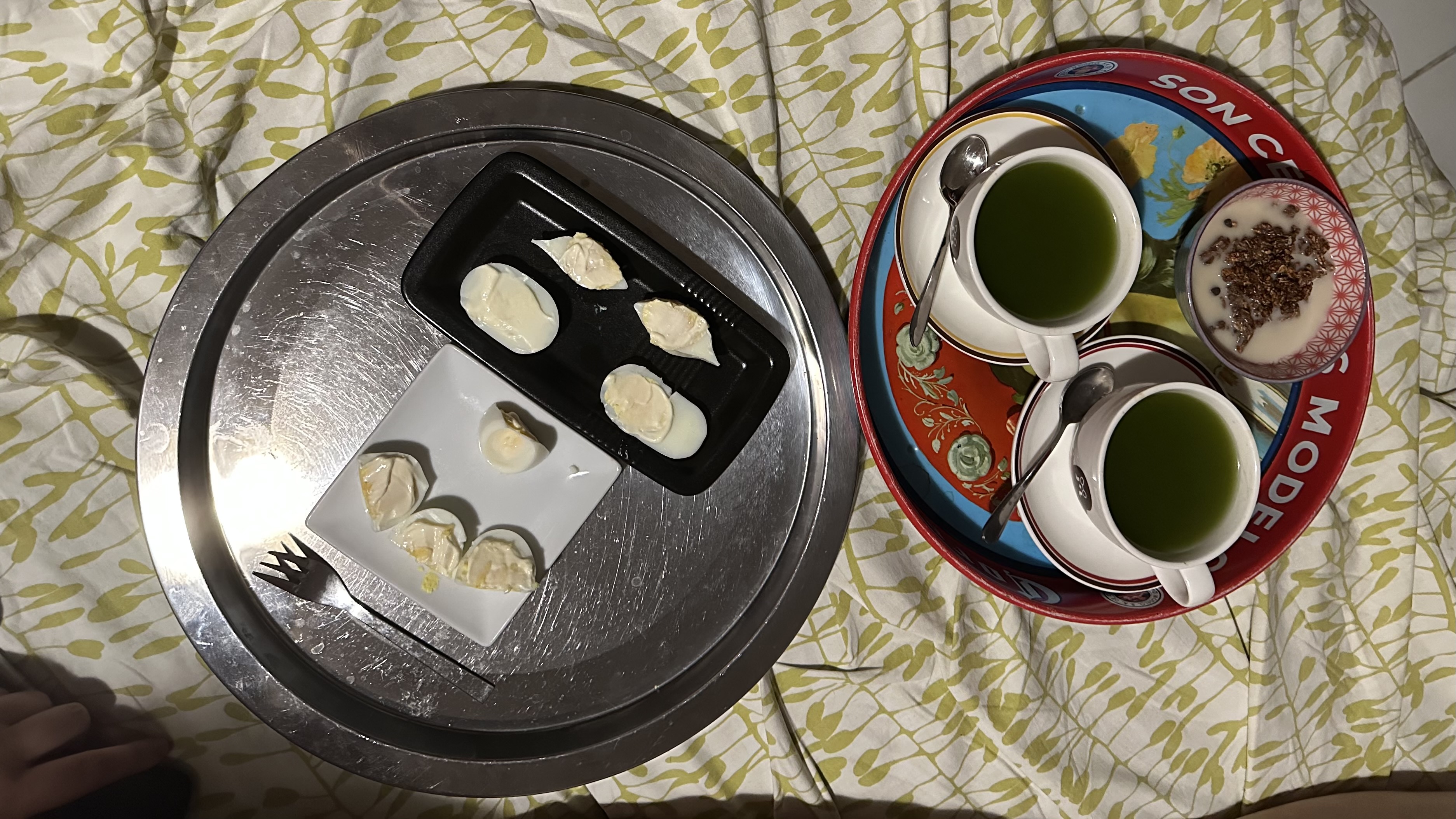 Deux plateaux de petit déjeuner, un bol de céréales, deux tasses de thé vert très vert, et un grand visage absurde composé avec deux œufs durs
